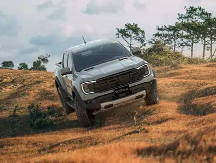 Xe Ford Ranger Raptor màu xám đang di chuyển vượt địa hình đồi dốc.
